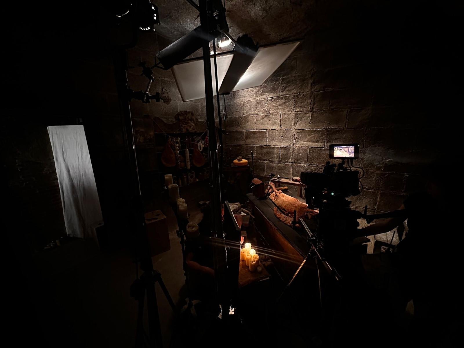 Stone interior lit by candles, with camera and monitor rigged over the scene