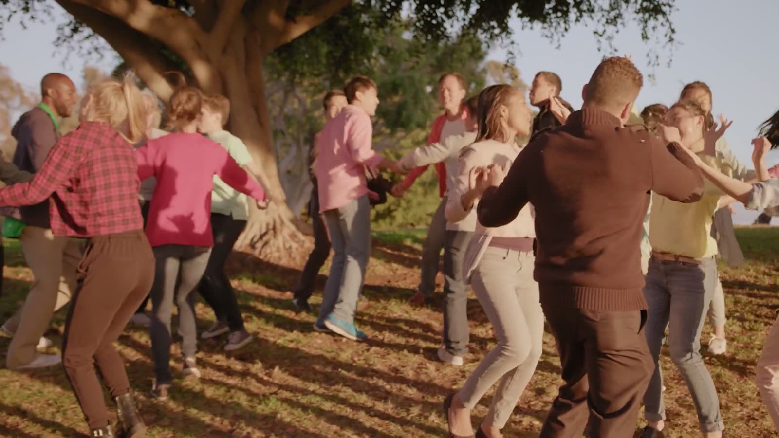 Fotograma de «Millennial Kingdom»: grupo numeroso bailando bajo los árboles