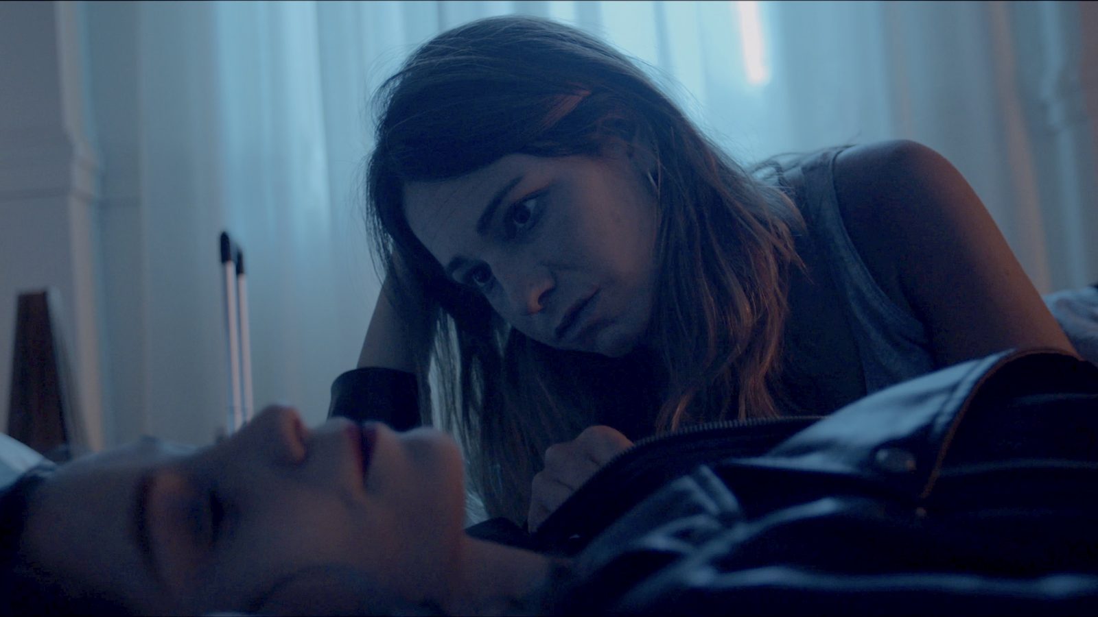 Fotograma de «Emily & Eva»: dos mujeres frente a frente en penumbra azulada