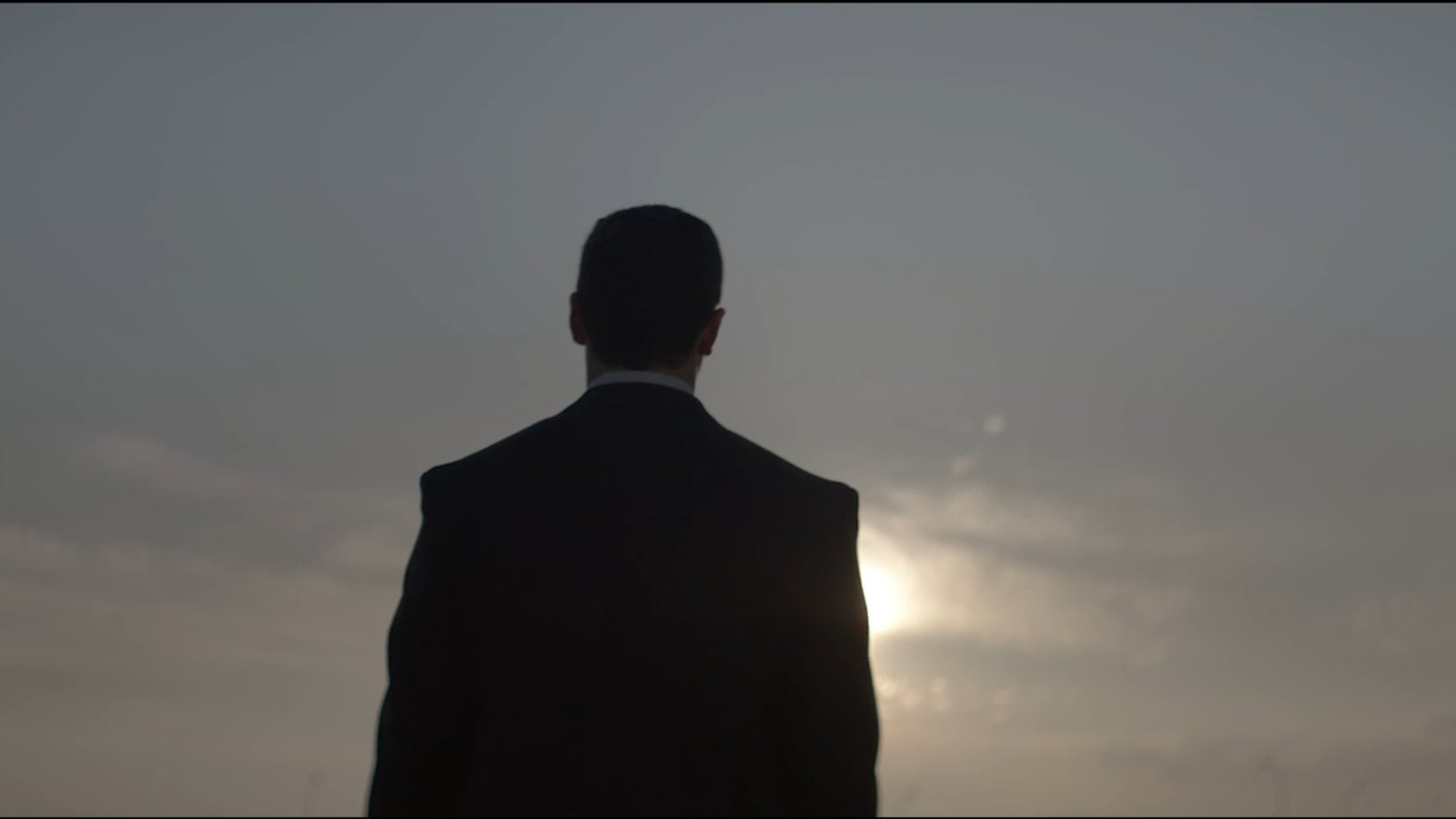 Fotograma del corporativo de Ferrovial: hombre de espaldas recortado contra el cielo al atardecer