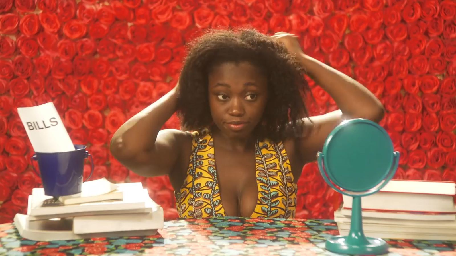 Fotograma de «Shea Buttah»: protagonista ante un muro de rosas rojas