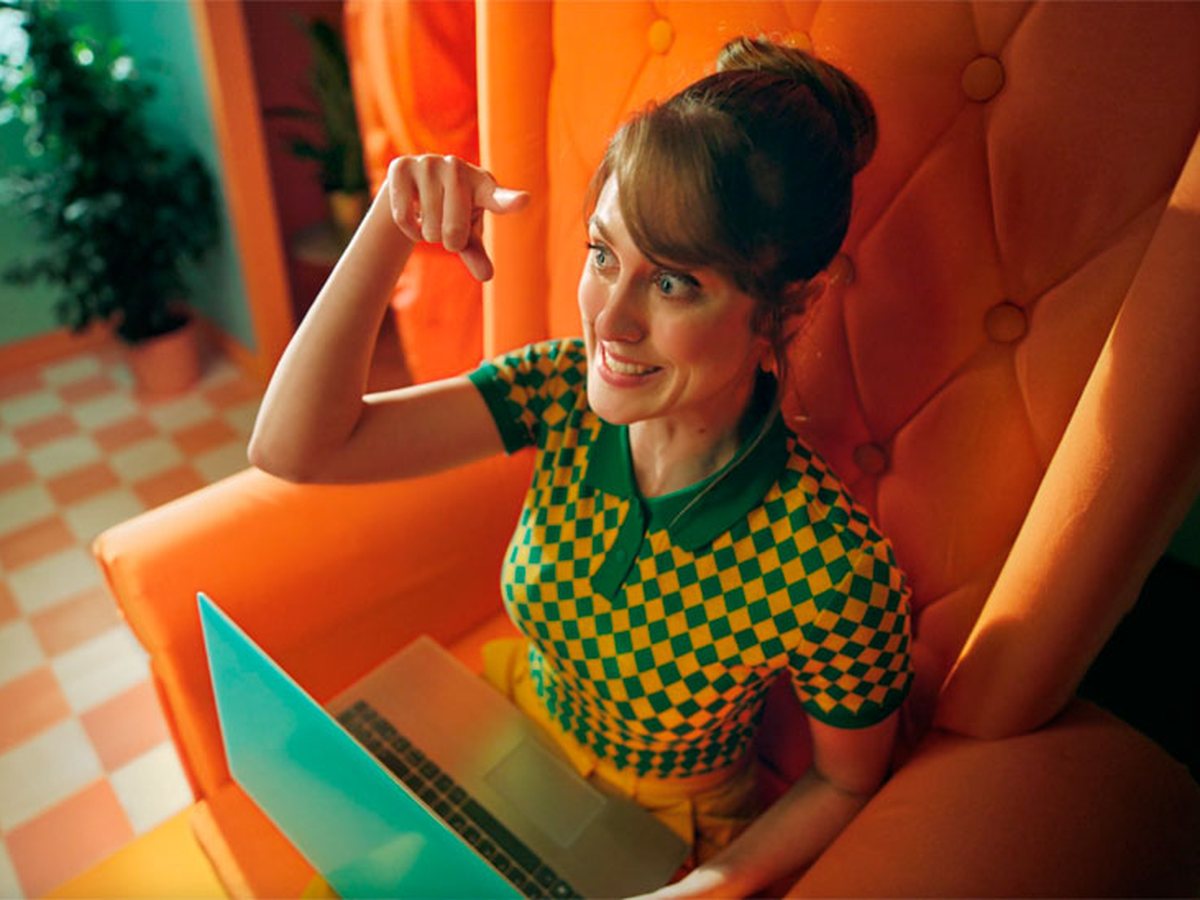 Imagen de la campaign «Así, sí» de Simyo: mujer con laptop en un sillón naranja